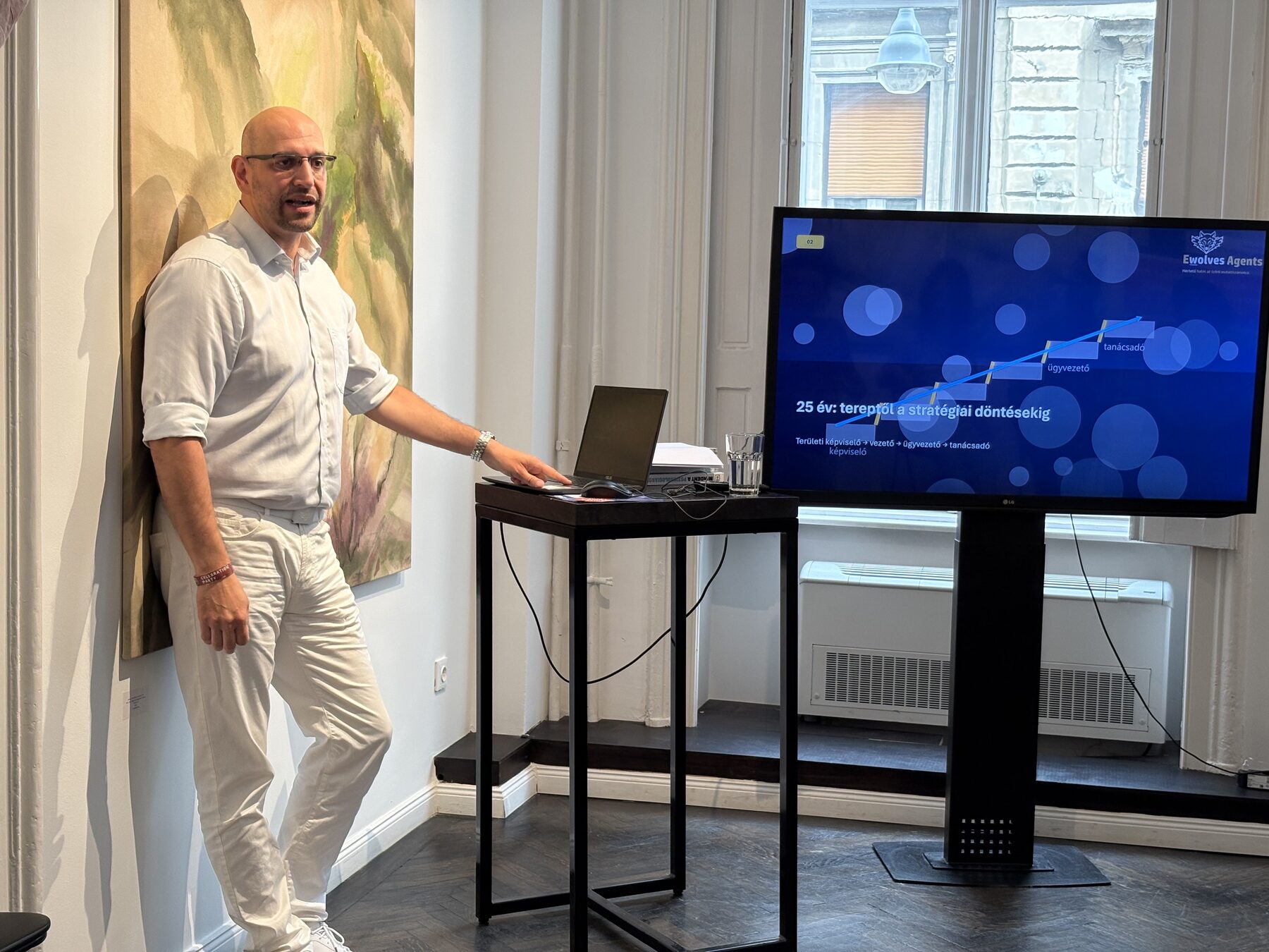 Előadó a monitor és a laptop mellett a beszéd közben